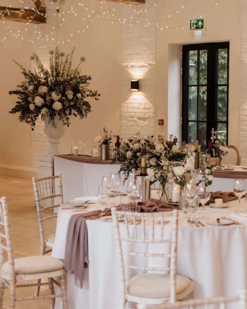 Wedding breakfast at Shotesham Park featuring urns of florals, top table arrangement and centrepieces. In shades of dusky lilac and white.