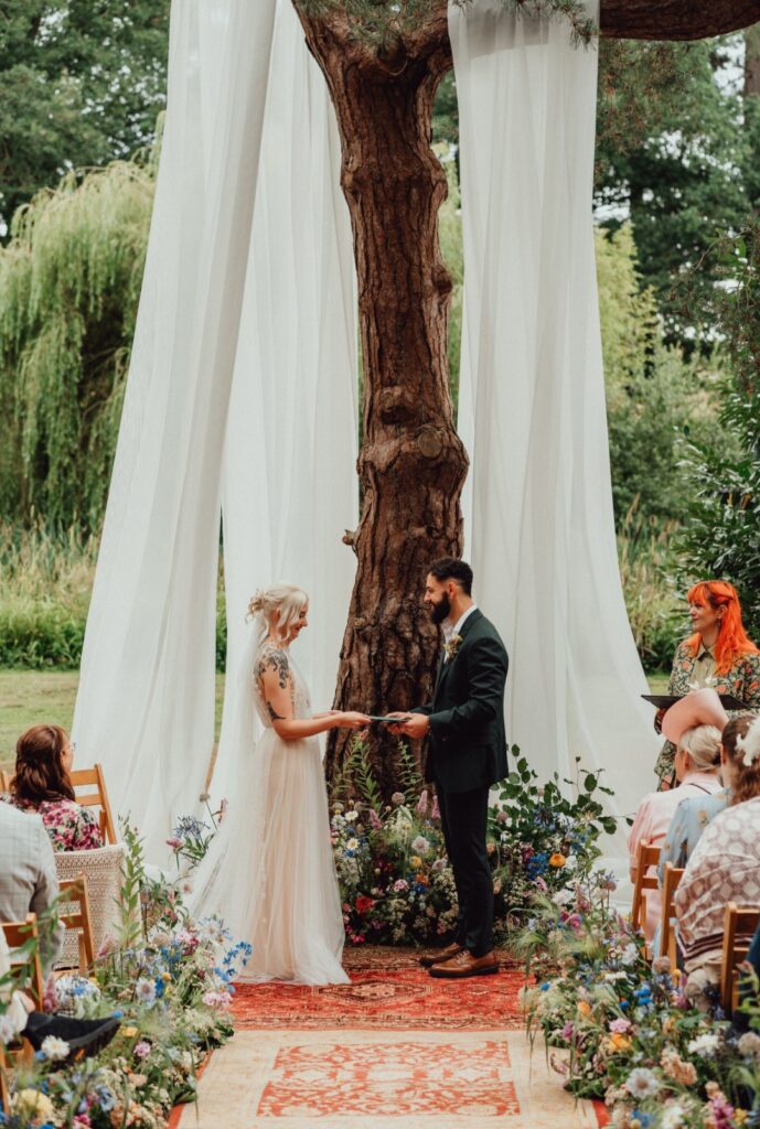 Hannah and Edward at Happy Valley Woodland Venue in Norfolk. Outside ceremony dressed with natural meadow florals