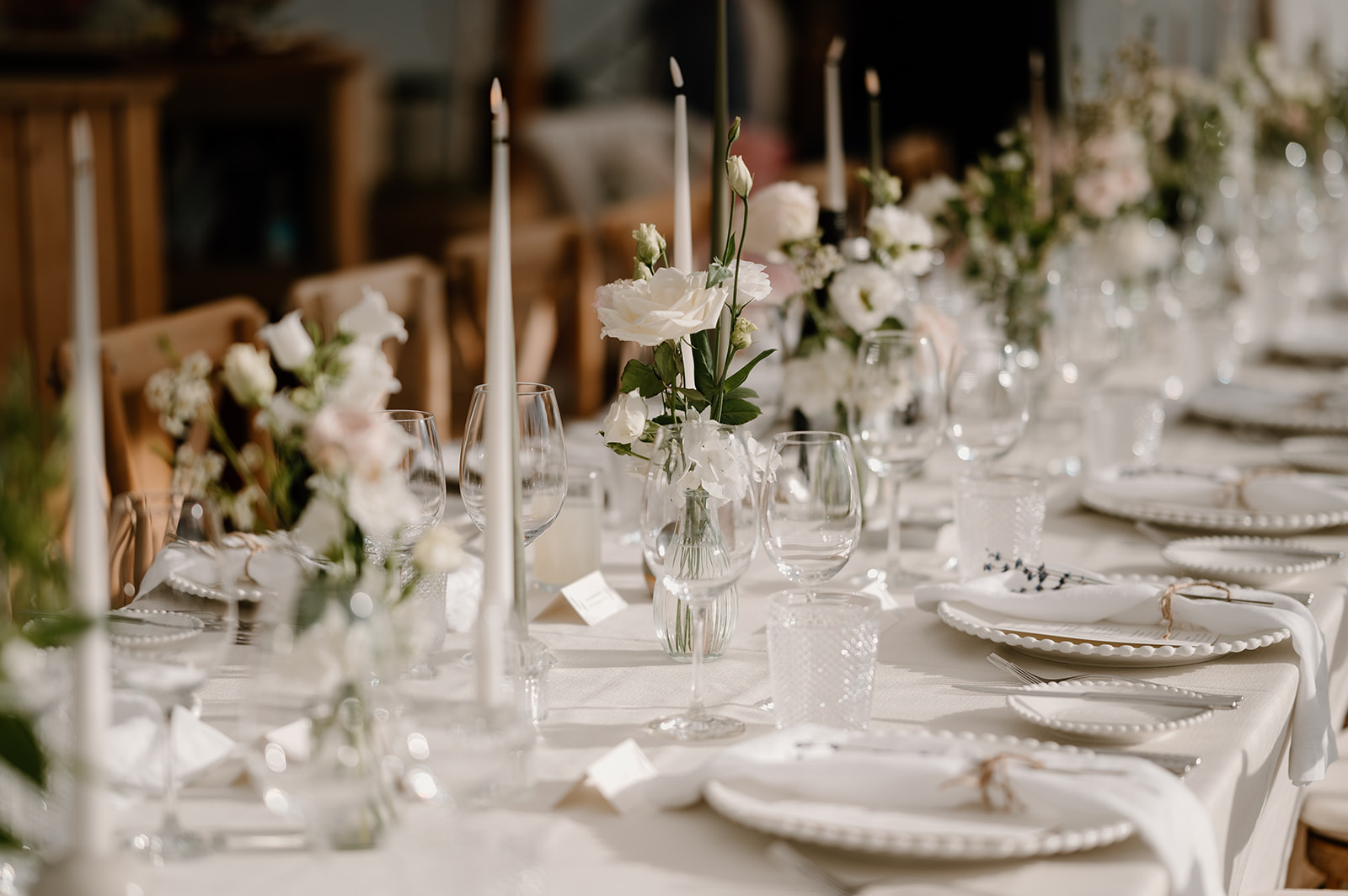 Marquee reception long tables dressed with bud vases filled with white and blush florals at Low Barn Farm Wedding venue in Norfolk
