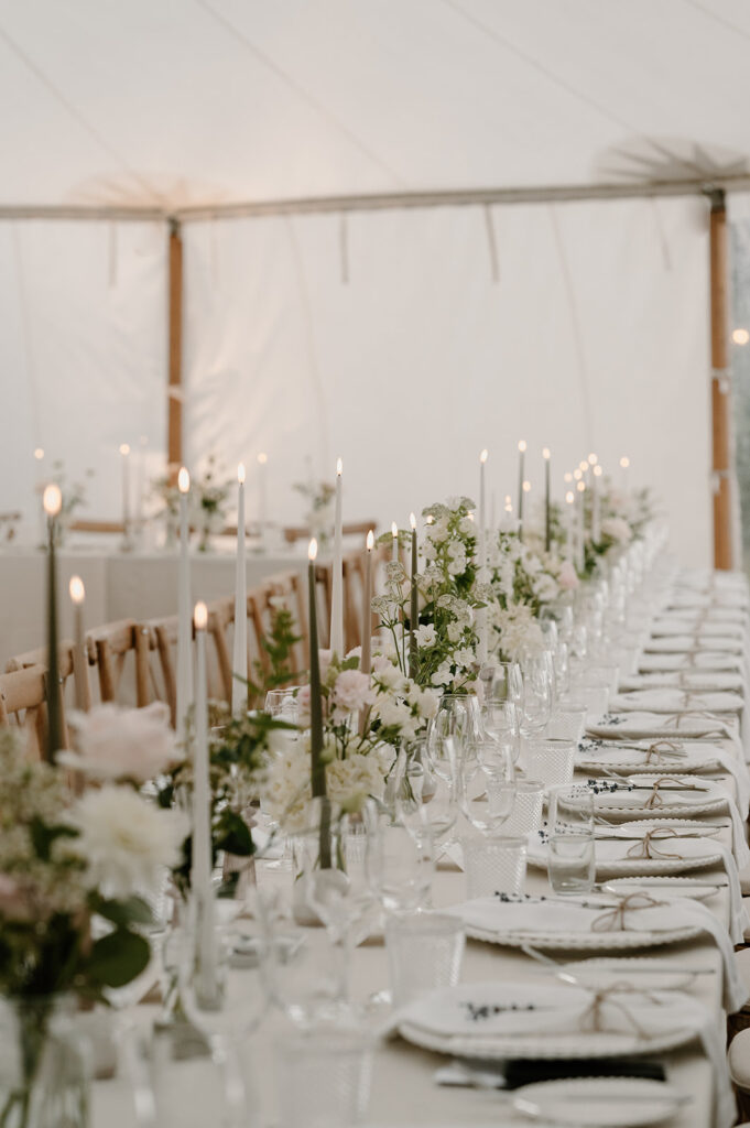 Long table bud vases of white and blush flowers for Hattie and Leos marquee wedding at Low Barn Farm Wedding venue in Norfolk 