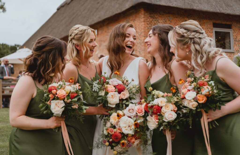 Bridal and bridesmaids bouquets in shades of orange, peach, dusky pink and white at The Woodyard Worstead Estate in Norfolk
