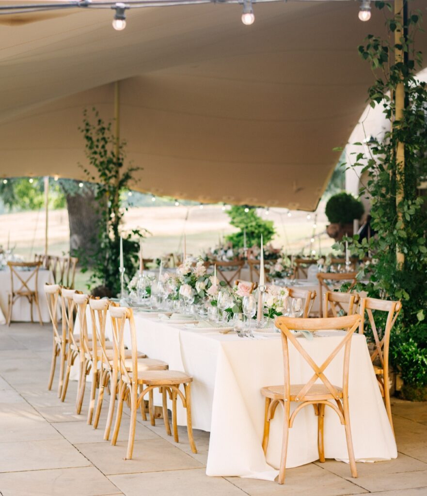 Sail cloth marquee wedding at Wilderness Reserve wedding venue in Suffolk. Featuring raised table floral centrepieces with added bud vases of florals in white and blush 