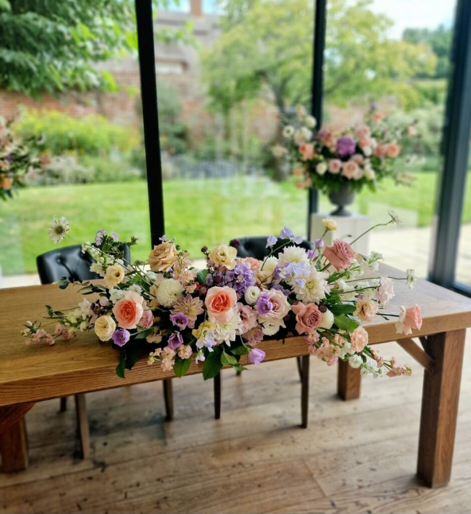 Modern relaxed ceremjny arrangements for Kayleigh and Ben at The Norfolk Mead Hotel. Featuring summer flowers in shades of lilac, peach, white, dusky pink and plum