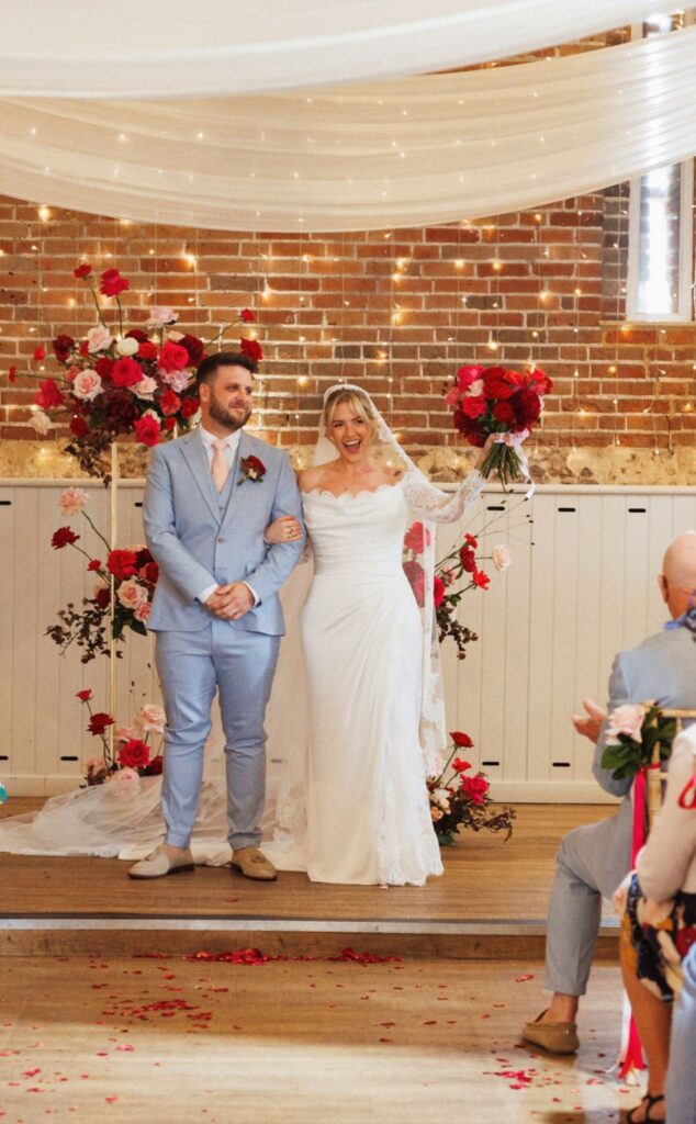 Modern wedding ceremony flowers in tones of red, burgundy and blush pink at Manor Mews wedding venue for Kellie & James. 