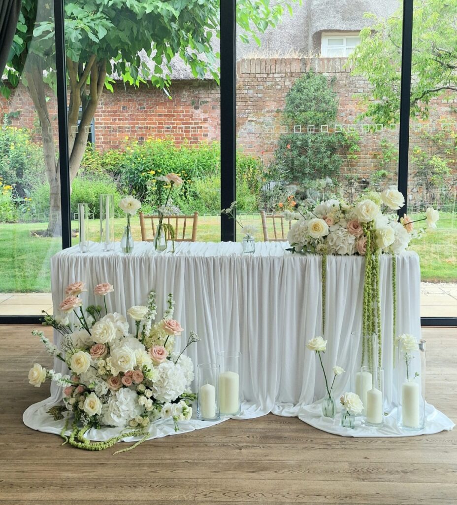 Modern styled wedding ceremony flowers at The Norfolk Mead Hotel including blousy roses, hydrangeas and amaranthus in shades of white and blush pink