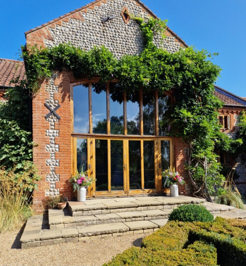 Milk churns filled with natural colourful wedding flowers at Chaucer Barn for Ellie and Sam
