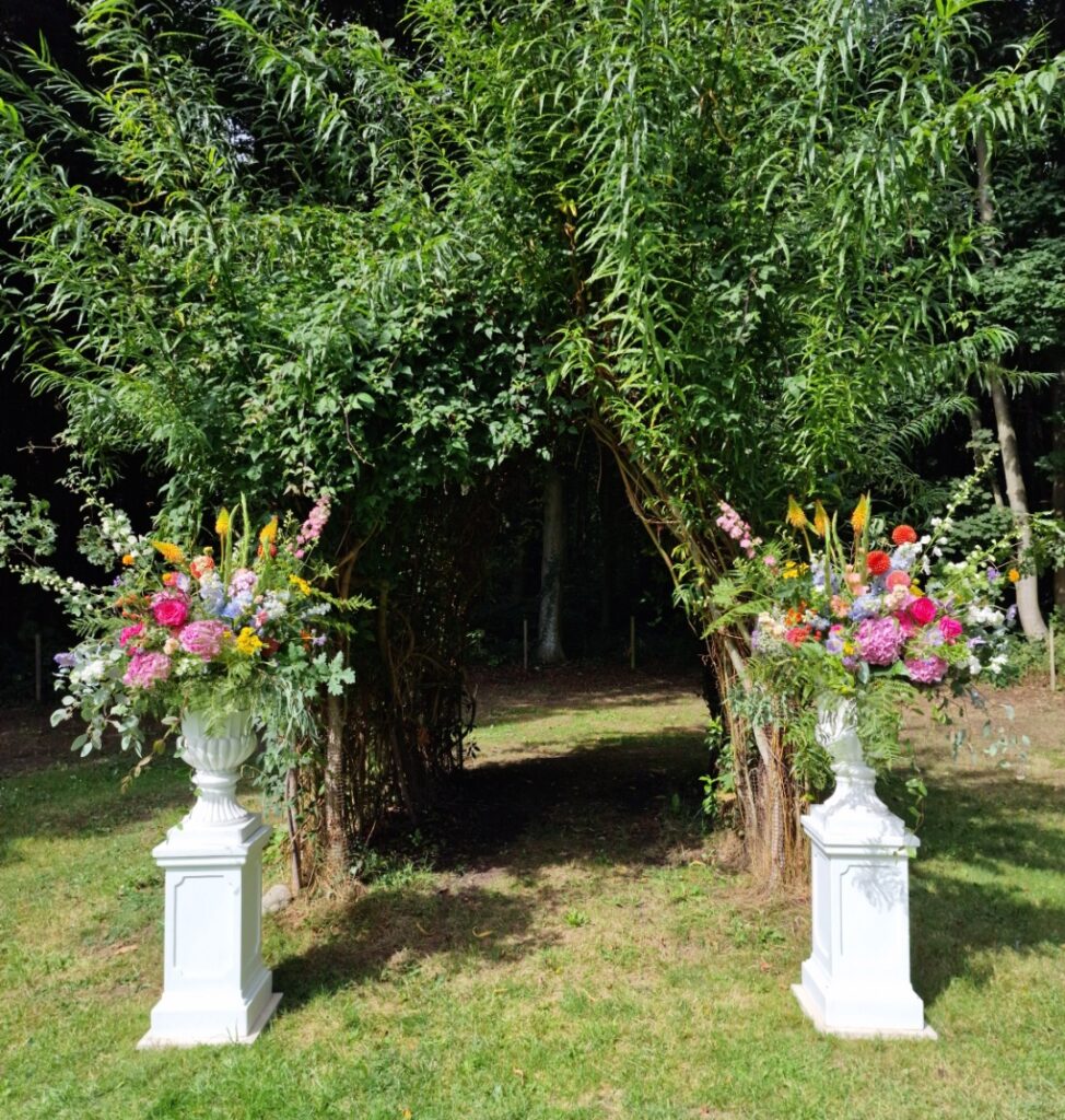 Ceremony urns of natural colourful flowers at the woodland meadow Chaucer Barn