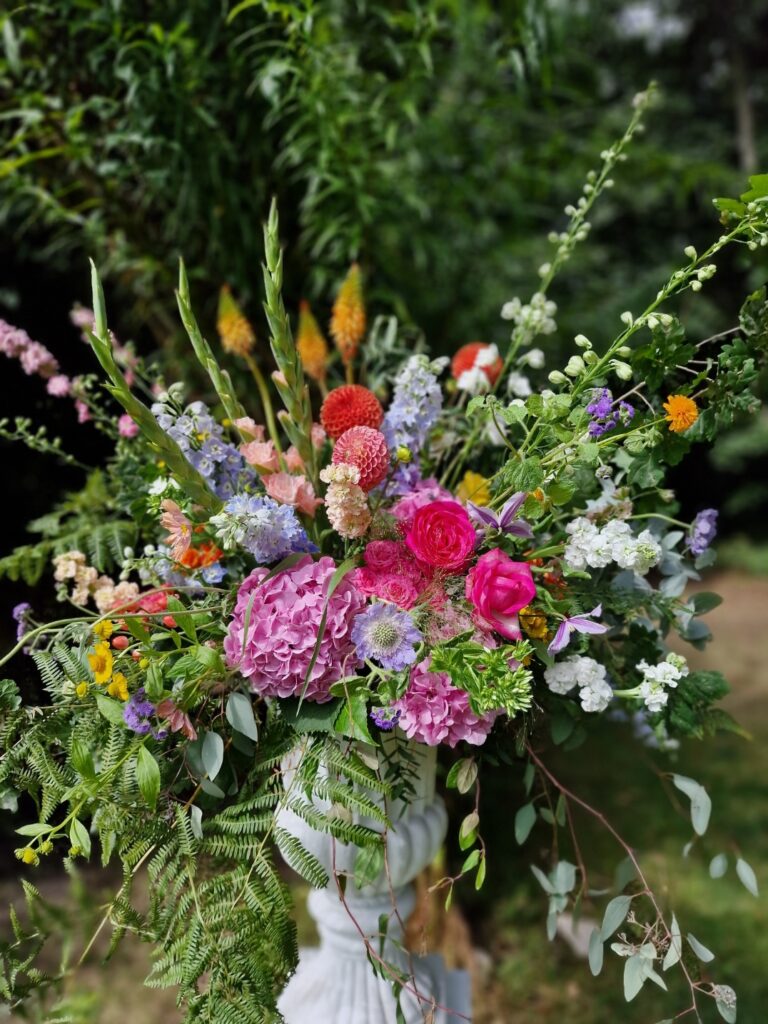 Bright natural urns of flowers for a wedding ceremony at Chaucer Barn Norfolk for Ellie and Sam