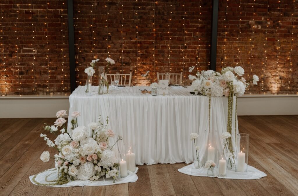 Modern wedding table flowers in shades of white and blush including bl8usy roses, hydrangea and amaranthus 
