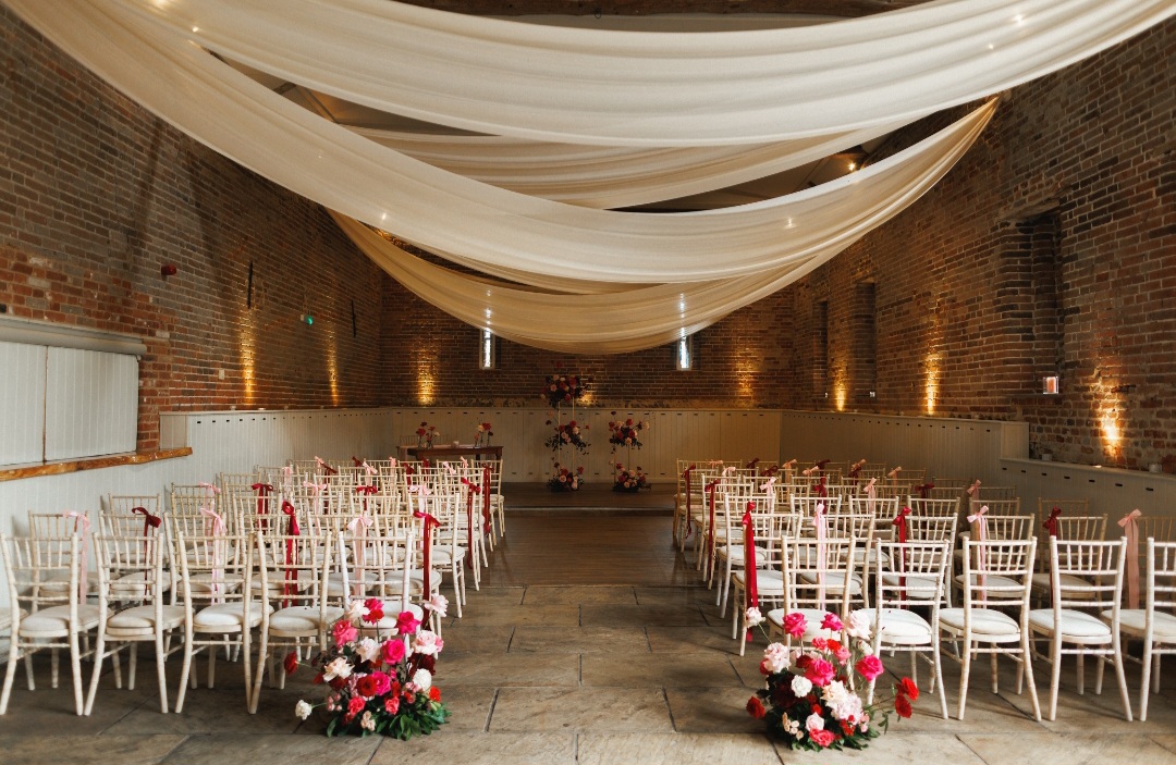 Modern wedding ceremjny flowers in shaddsnof red, burgundy and pink at Manor Mews wedding venue